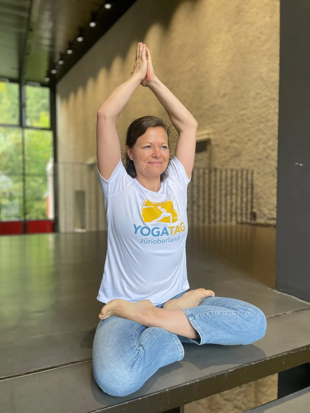Daniela sitzt in Yogastellung auf dem Boden.